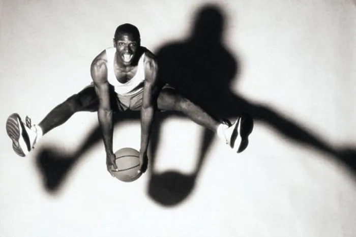 Framed Print : Portrait of a young man holding a basketball jumping up in the air