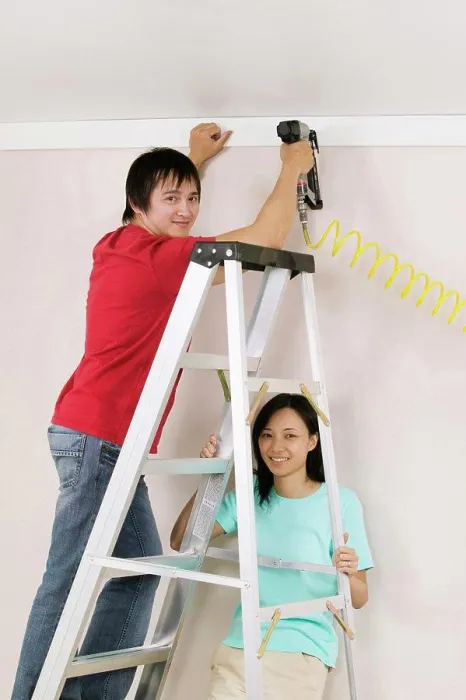 Framed Print : Portrait of a young man using a drill on a wall with a young woman holding a ladder Framed Print : Portrait of a young man using a drill on a wall with a young woman holding a ladder