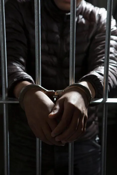 Framed Print : A prisoner behind bars with hands cuffed Framed Print : A prisoner behind bars with hands cuffed