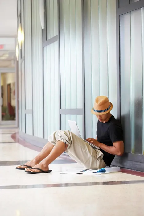 Framed Print : Side profile of a college student sitting in a corridor and using a laptop Framed Print : Side profile of a college student sitting in a corridor and using a laptop