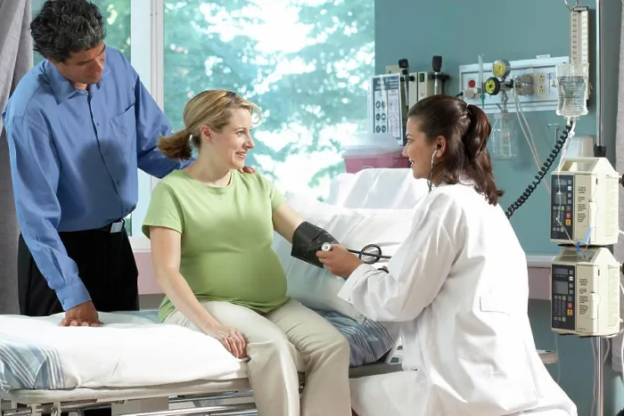 Framed Print : Side profile of a female doctor checking the blood pressure of a pregnant woman