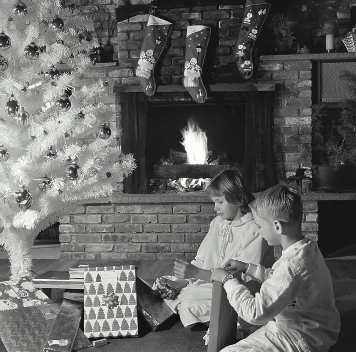 Framed Print : Side profile of a girl and her brother unwrapping Christmas presents near a fireplace Framed Print : Side profile of a girl and her brother unwrapping Christmas presents near a fireplace