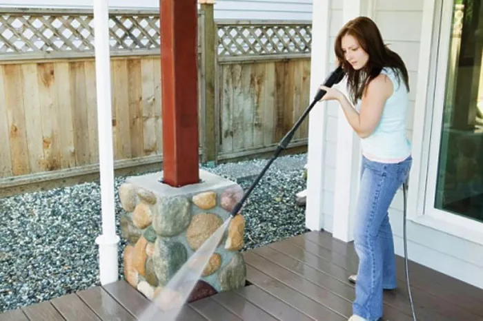 Framed Print : Side profile of a young woman cleaning the porch of her house Framed Print : Side profile of a young woman cleaning the porch of her house
