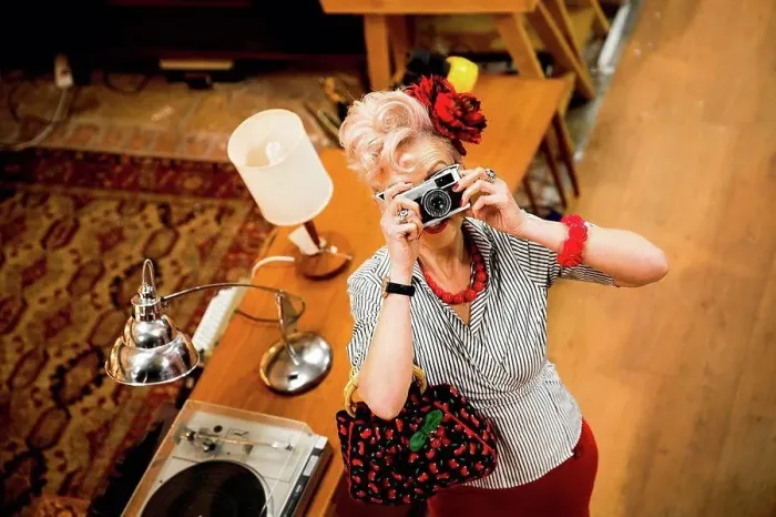Framed Print : Quirky woman taking photographs on vintage camera in antiques emporium