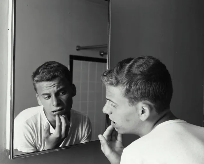Framed Print : Rear view of a teenage boy looking at a mirror with his hand on his chin, 1960 Framed Print : Rear view of a teenage boy looking at a mirror with his hand on his chin, 1960