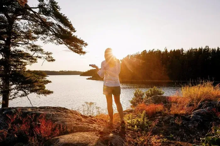 Framed Print : Rear view of woman holding mobile phone while standing on lakeshore at sunset Framed Print : Rear view of woman holding mobile phone while standing on lakeshore at sunset
