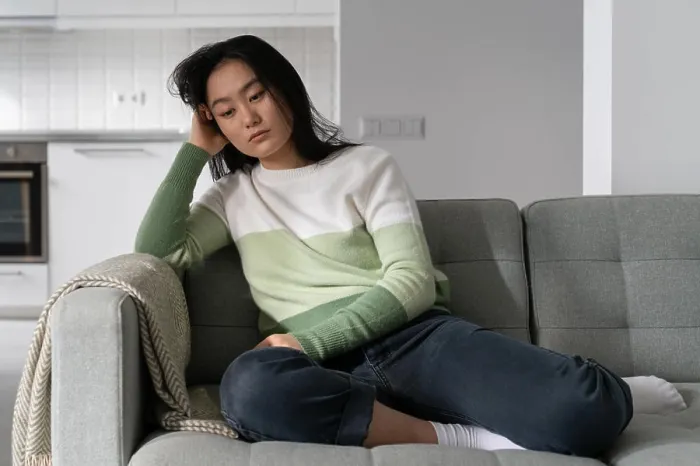 Framed Print : Sad, angry chinese sits on the sofa and suffers from depression after she has separated from her boyfriend Framed Print : Sad, angry chinese sits on the sofa and suffers from depression after she has separated from her boyfriend