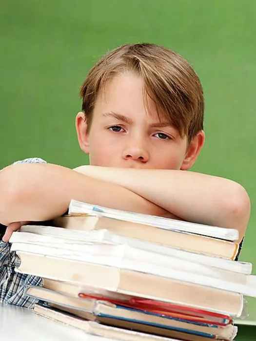 Framed Print : Schoolboy with a stack of books, looking frustrated, tired Framed Print : Schoolboy with a stack of books, looking frustrated, tired