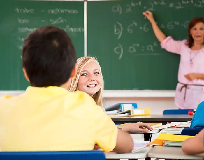 Framed Print : Schoolgirl turning around to her classmates during the class