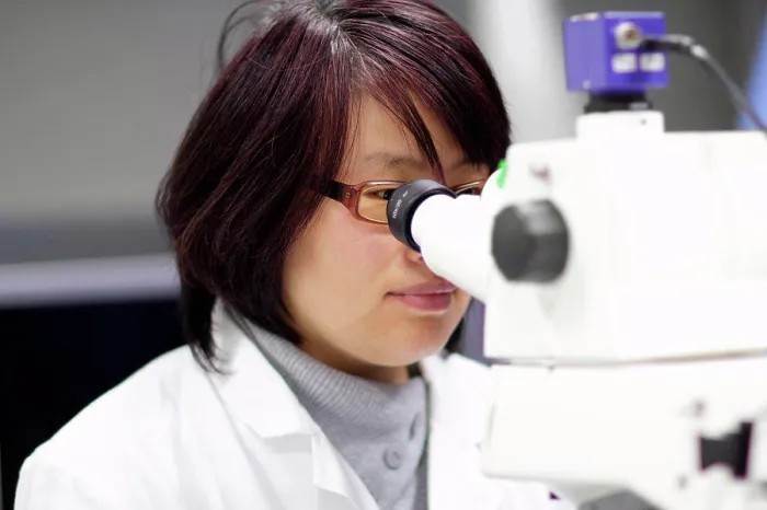 Framed Print : Scientist using microscope in lab