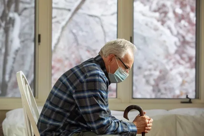 Framed Print : Senior man wearing protective mask sitting near window