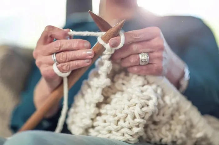 Framed Print : Senior woman knitting on couch at home
