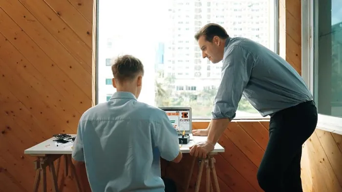 Framed Print : Skilled teacher looking at young highschool student fixing car model while laptop screen display coding engineering Framed Print : Skilled teacher looking at young highschool student fixing car model while laptop screen display coding engineering