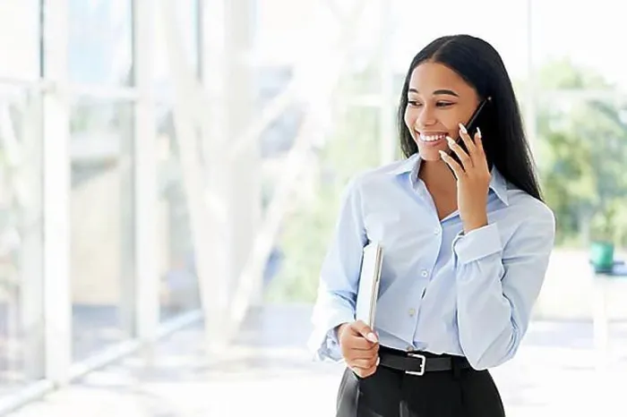 Framed Print : Smiling African American businesswoman talking on phone in open space modern office with panoramic windows background Framed Print : Smiling African American businesswoman talking on phone in open space modern office with panoramic windows background