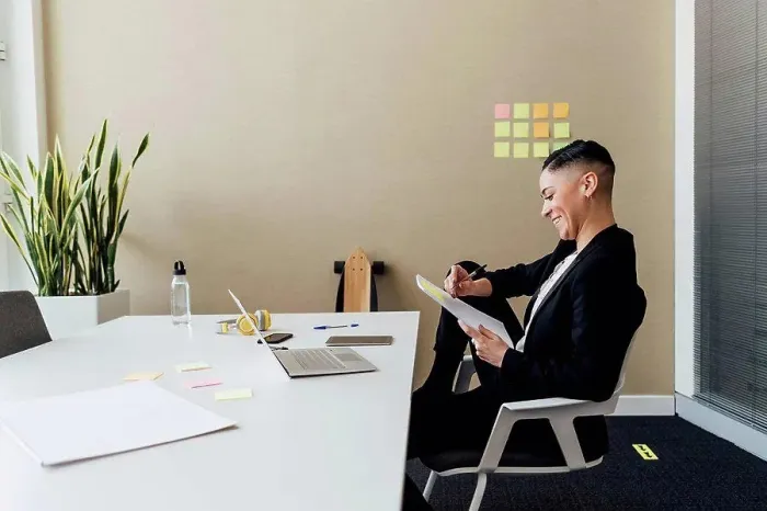 Framed Print : Smiling businesswoman writing on paper while sitting at desk in office Framed Print : Smiling businesswoman writing on paper while sitting at desk in office