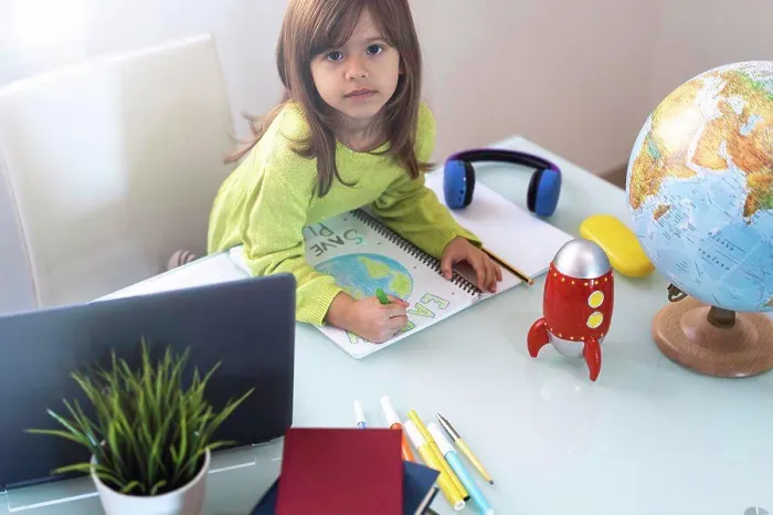 Framed Print : Smiling child girl draws planet earth with wax colors on school notebook for Earth day - Little activist girl writes