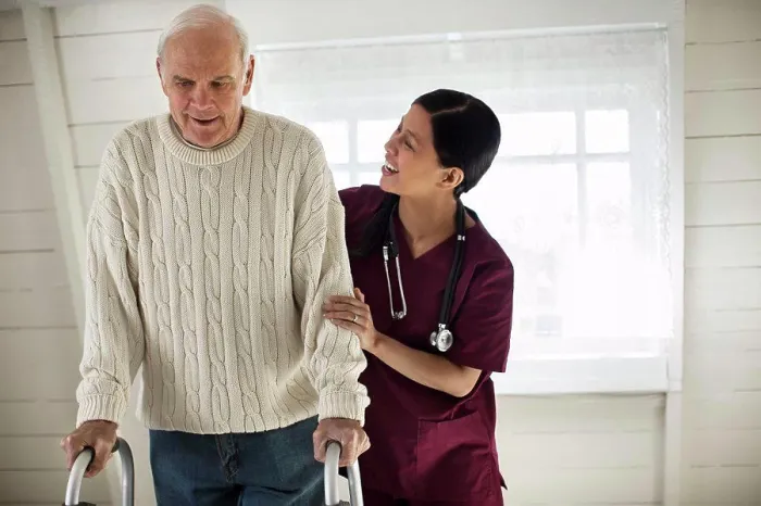 Framed Print : Smiling female nurse encouraging an elderly male patient as he uses a walking frame