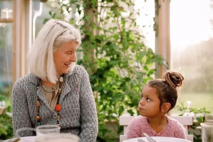 Framed Print : Smiling grandmother looking at granddaughter while having lunch Framed Print : Smiling grandmother looking at granddaughter while having lunch