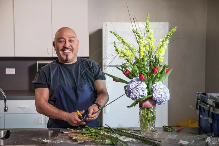 Framed Print : Smiling man arranging flowers in kitchen