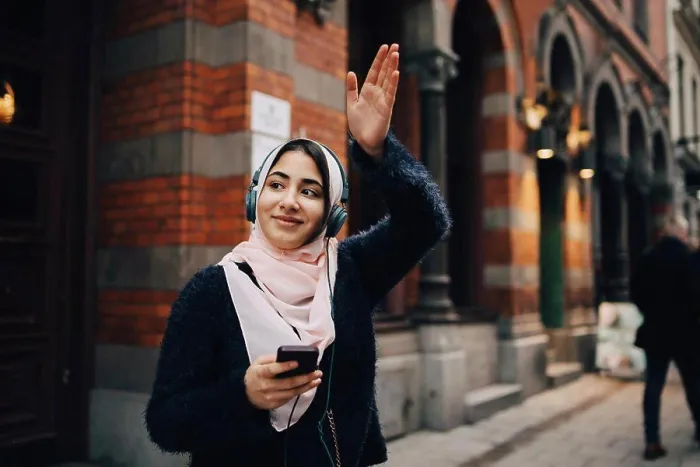 Framed Print : Smiling teenage girl waving hand while listening to headphones on footpath in city Framed Print : Smiling teenage girl waving hand while listening to headphones on footpath in city
