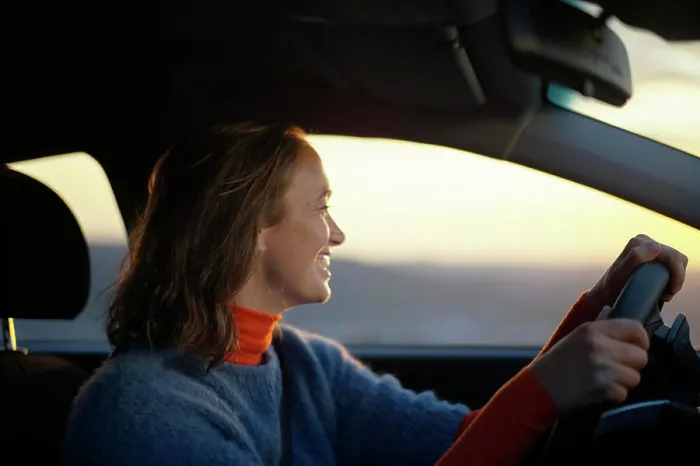 Framed Print : Smiling woman driving a car during sunset with warm light illuminating her face Framed Print : Smiling woman driving a car during sunset with warm light illuminating her face