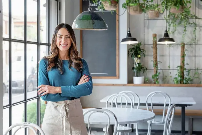 Framed Print : Smiling woman standing with arms crossed in cafe Framed Print : Smiling woman standing with arms crossed in cafe