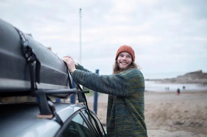 Framed Print : Smiling young man fastening canoe onto car at beach Framed Print : Smiling young man fastening canoe onto car at beach