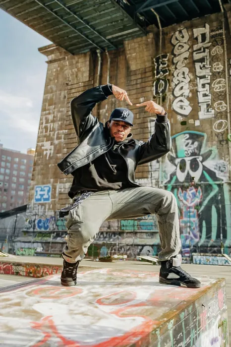 Framed Print : Street dancer strikes pose on graffiti-covered ledge under bridge