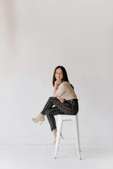 Framed Print : Studio shot of young woman sitting on stool Framed Print : Studio shot of young woman sitting on stool