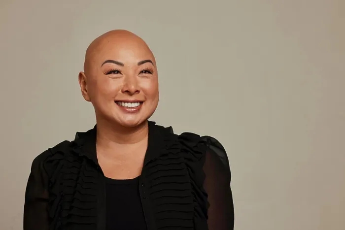 Framed Print : Stylish woman with a bald head smiling against a neutral backdrop Framed Print : Stylish woman with a bald head smiling against a neutral backdrop