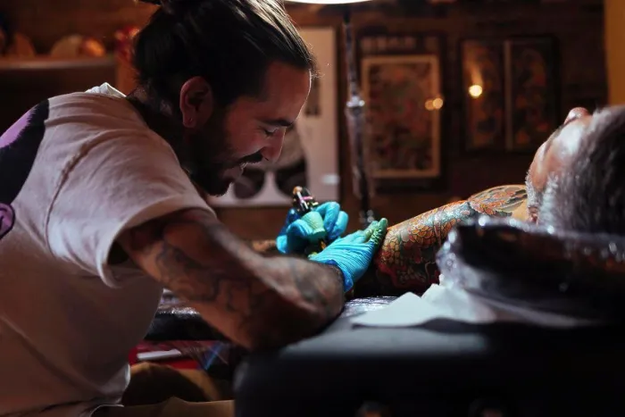 Framed Print : Tattoo artist enjoys while working on a customer's arm in his studio Framed Print : Tattoo artist enjoys while working on a customer's arm in his studio