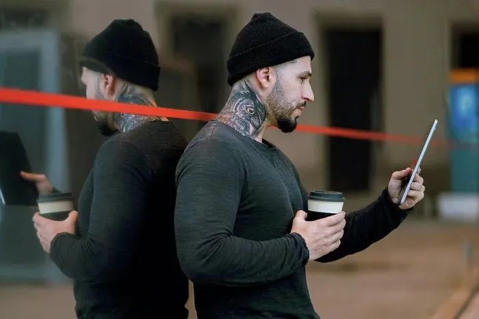 Framed Print : Tattooed hipster man with coffee cup using digital tablet while leaning on glass Framed Print : Tattooed hipster man with coffee cup using digital tablet while leaning on glass