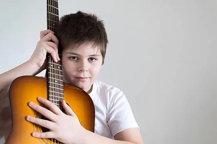 Framed Print : Teenage Boy plays an acoustic guitar while relaxing on a patio chair