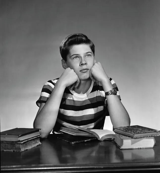 Framed Print : teenage boy sitting wit books open and looking away Framed Print : teenage boy sitting wit books open and looking away