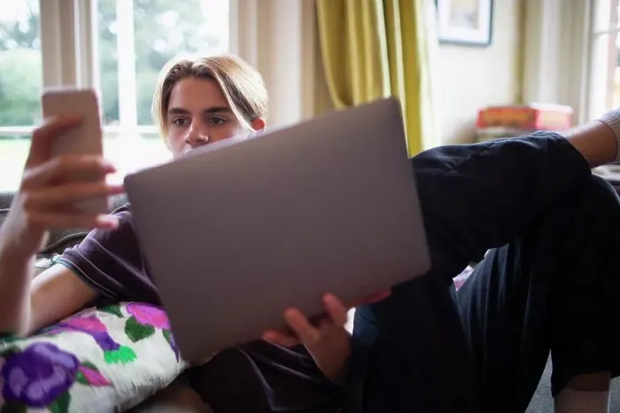 Framed Print : Teenage boy using smart phone and laptop at home