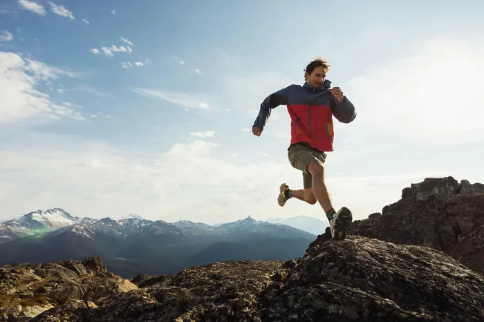 Framed Print : Trail runner in a red jacket navigating rocky mountain terrain