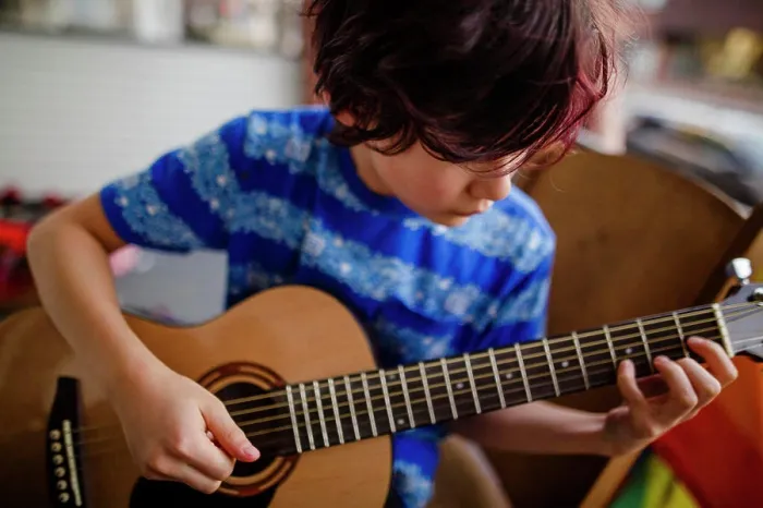 Framed Print : Tween boy tenderly plays an acoustic guitar on front porch of home Framed Print : Tween boy tenderly plays an acoustic guitar on front porch of home