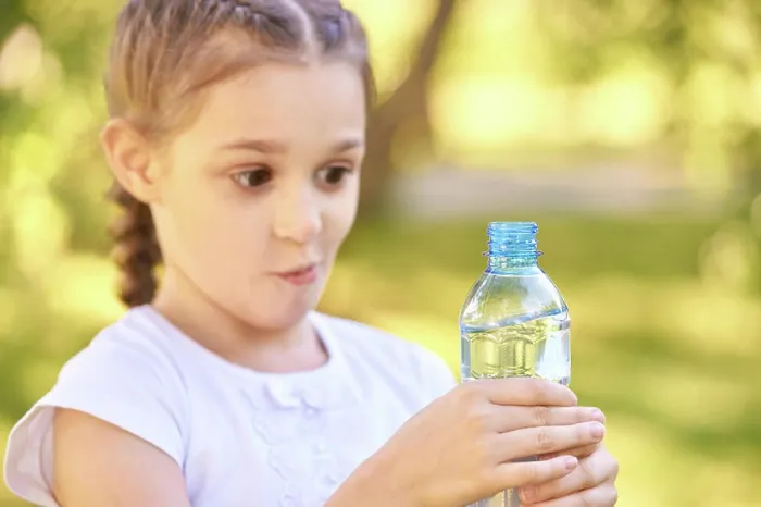 Framed Print : Überrascht kaukasischen weiblichen Kind hält Wasserflasche außerhalb in sonnigen Park Surprised caucasian female child