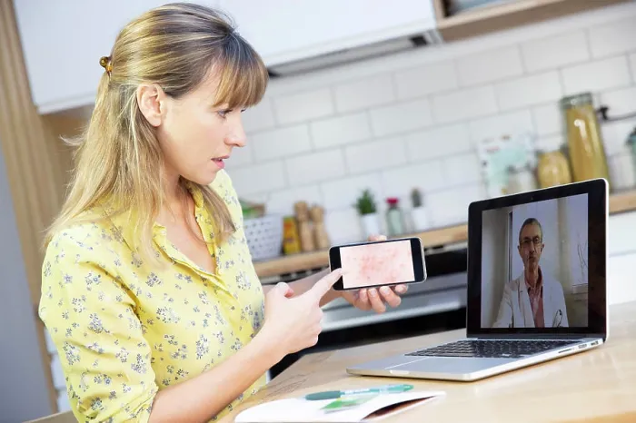 Framed Print : A video consultation between a young woman and her GP for a heat rash that she has taken a photo of using her mobile Framed Print : A video consultation between a young woman and her GP for a heat rash that she has taken a photo of using her mobile
