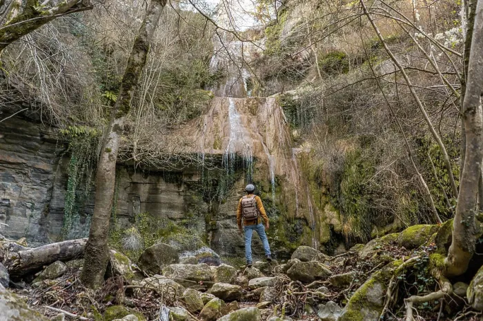 Framed Print : Back view of male traveler with outstretched arms standing on stones and admiring fantastic waterfall in forest in Spain Framed Print : Back view of male traveler with outstretched arms standing on stones and admiring fantastic waterfall in forest in Spain