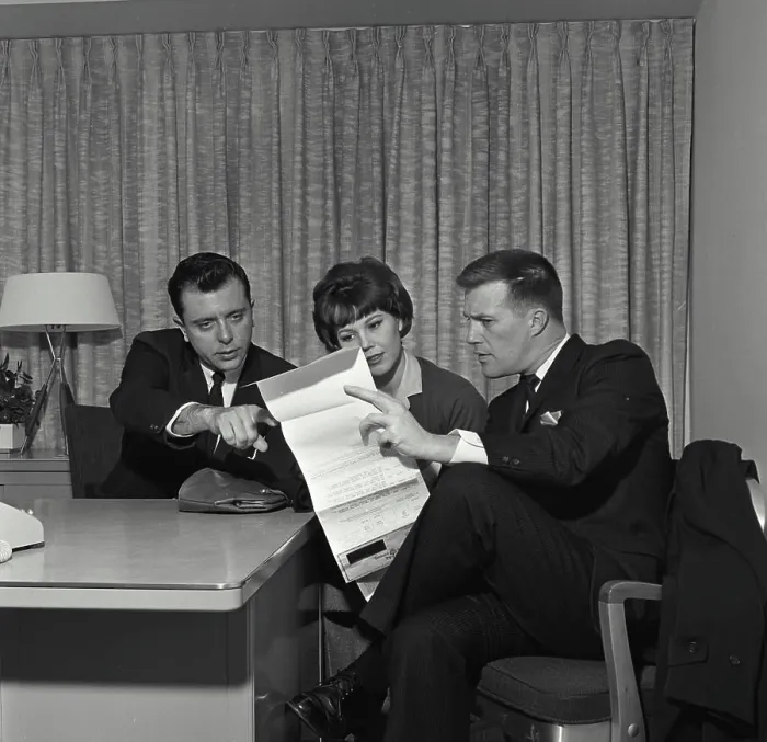 Framed Print : Vintage Photograph. A businessman and a couple sitting at a desk reviewing a credit contract Framed Print : Vintage Photograph. A businessman and a couple sitting at a desk reviewing a credit contract