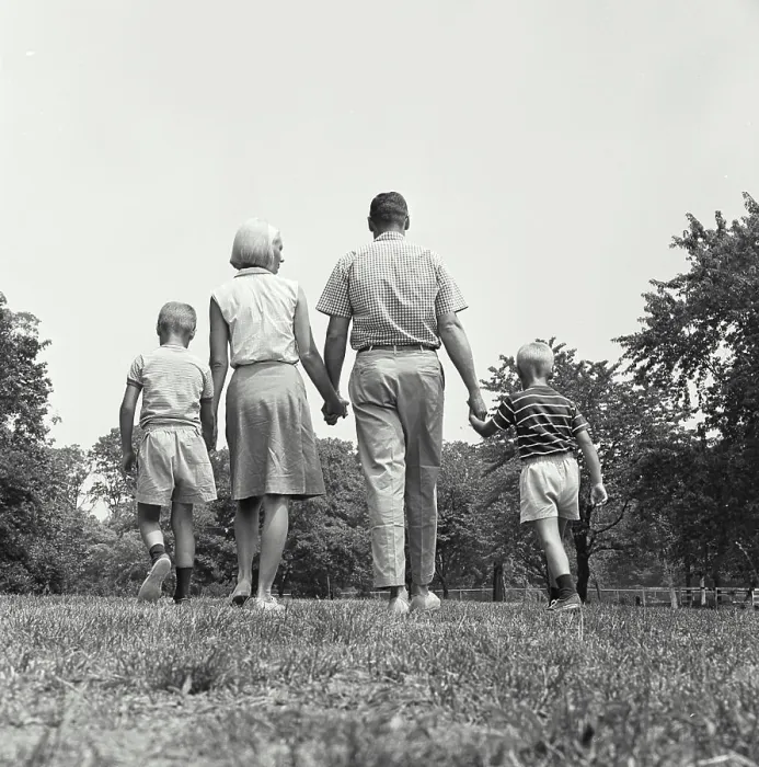 Framed Print : Vintage Photograph. A family group walking holding hands away from camera
