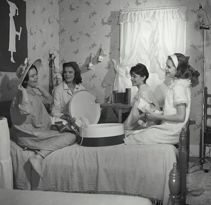 Framed Print : Vintage Photograph. A group of young girls at slumber party trying on floral hat