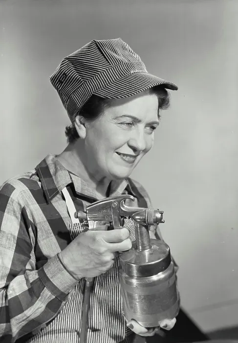 Framed Print : Vintage photograph. Middle aged woman dressed in work uniform holding paint sprayer with fingers on trigger