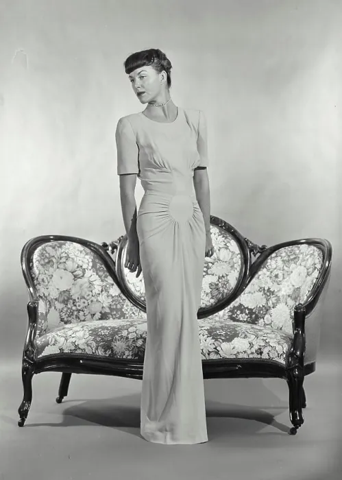Framed Print : Vintage photograph. Woman in full length dress standing in front of small settee couch Framed Print : Vintage photograph. Woman in full length dress standing in front of small settee couch