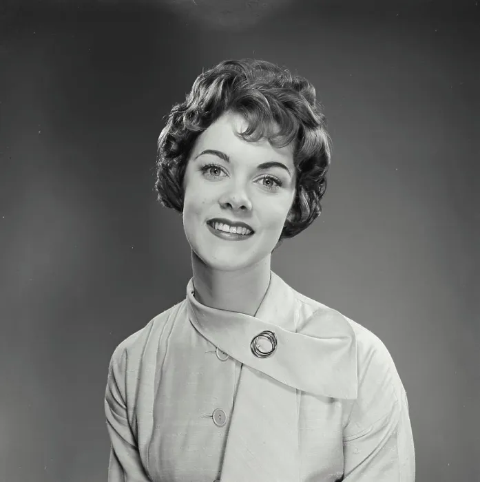 Framed Print : Vintage Photograph. Woman wears a white dress with a brooch and smiles for studio portrait while looking at the camera Framed Print : Vintage Photograph. Woman wears a white dress with a brooch and smiles for studio portrait while looking at the camera