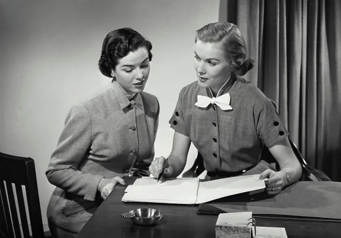 Framed Print : Vintage Photograph. Two women in business office sitting at desk having conversation Framed Print : Vintage Photograph. Two women in business office sitting at desk having conversation