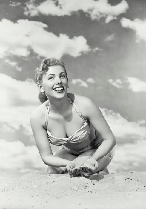 Framed Print : Vintage photograph. Young smiling woman in swimsuit kneeling in sand with sky background