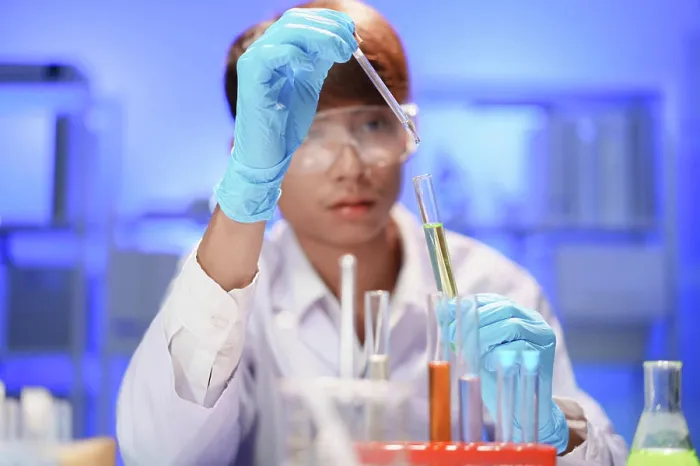 Framed Print : Wissenschaftler, die im Labor arbeiten und mit einer Pipette eine flüssige Probe in ein Reagenzglas tropfen