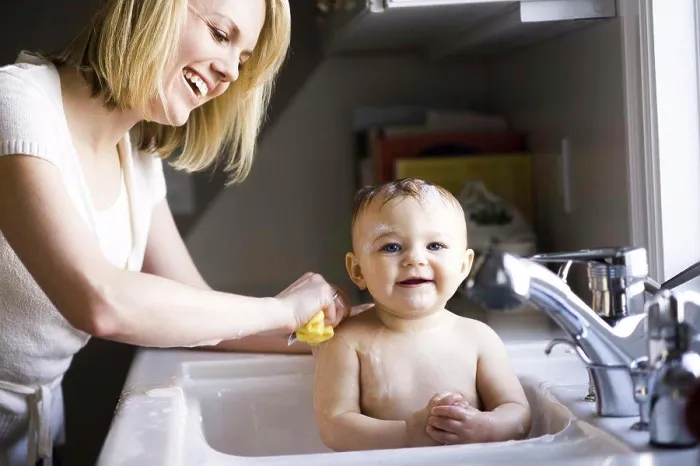 Framed Print : Woman bathing baby in sink Framed Print : Woman bathing baby in sink